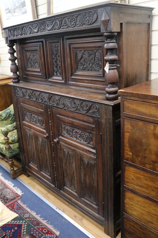 A 17th century style carved oak press cupboard W.140cm